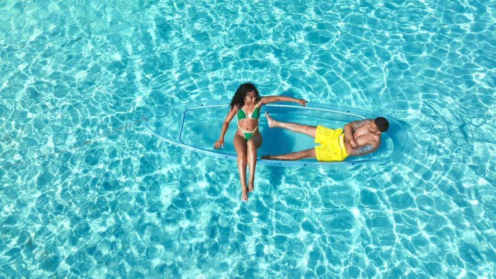 Drone shot: couple lying side by side in a clear kayak in Aruba