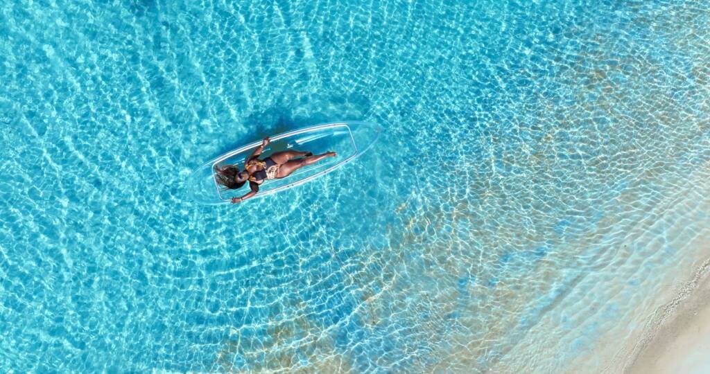 Drone shot: person relaxing in a clear kayak near the shoreline in Aruba