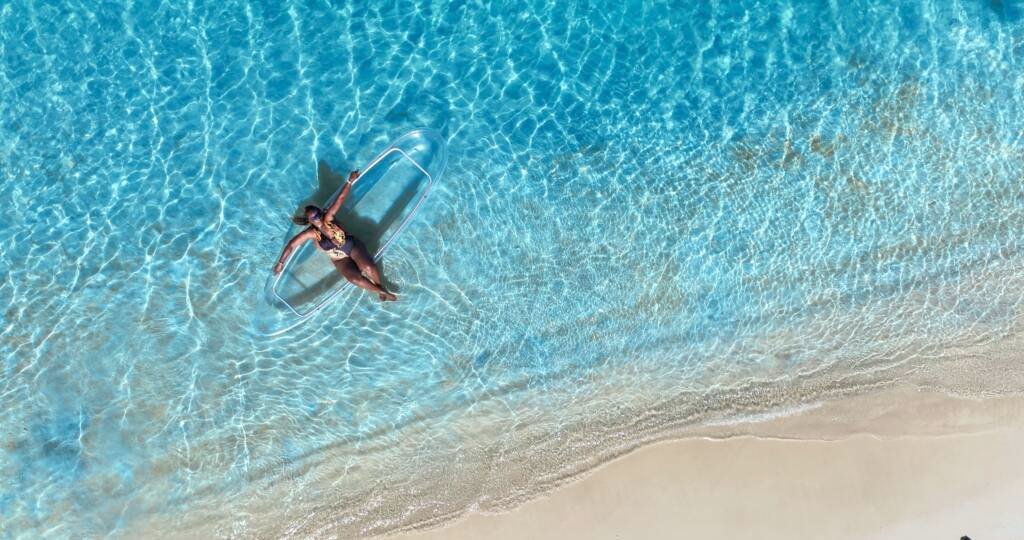 Drone shot: person in a clear kayak along the shoreline in Aruba