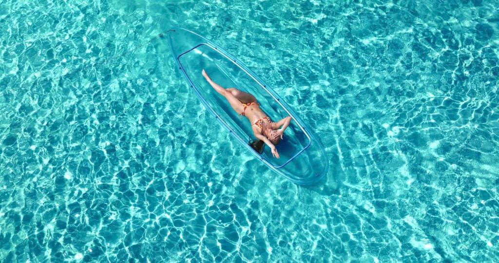 Drone shot: person stretched out in a clear kayak in Aruba